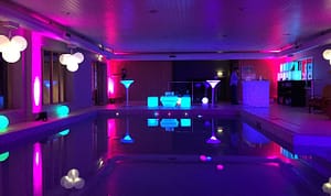 Image of a swimming pool decorated for a birthday party with creative lighting and furniture.