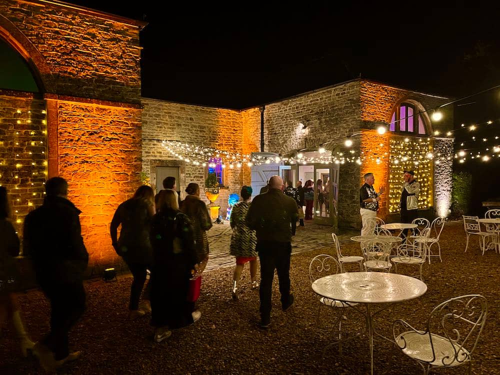 Pennard House Lighting with Amber Up-lighting Pennard House Somerset with people arriving for a party in the Coach House